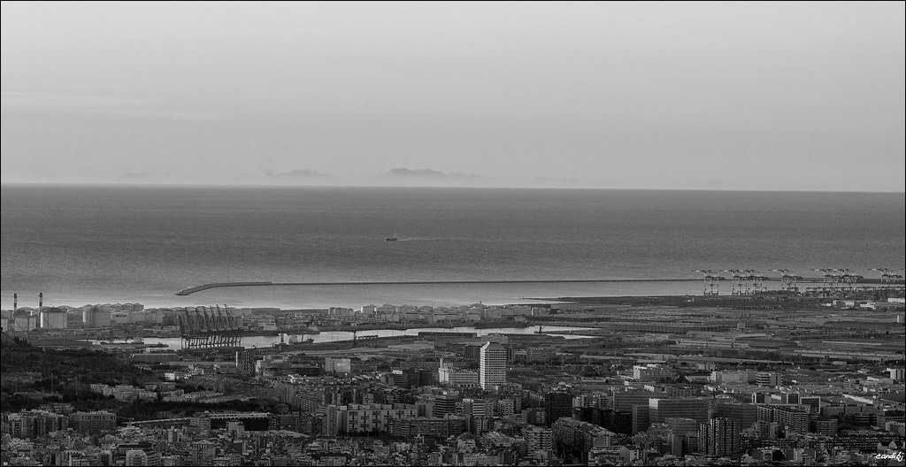 The serrated silhouette of the Serra de Tramuntana floating on the sea horizon beyond Barcelona's port, photographed at dawn
