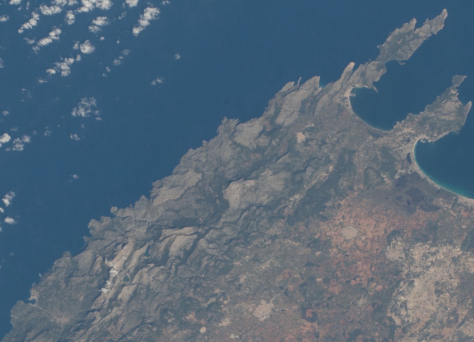 Mallorca's north-west coast from the International Space Station: the Serra de Tramuntana as one continuous grey rock wall along the coast, with the Formentor peninsula trailing off the top right and the island's flat interior behind