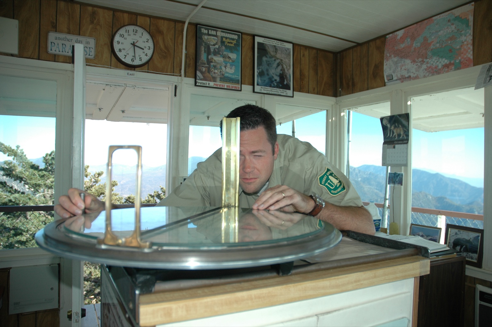 A US Forest Service lookout sighting a bearing on an Osborne Firefinder inside a tower cab